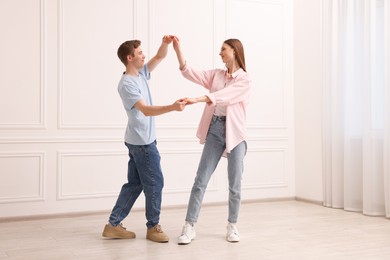 Photo of Happy couple dancing together near white wall at home