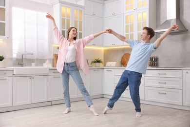 Photo of Happy young couple dancing together in kitchen