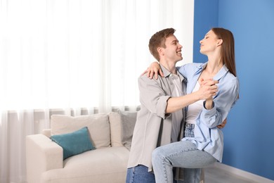 Photo of Happy couple dancing at home. Space for text