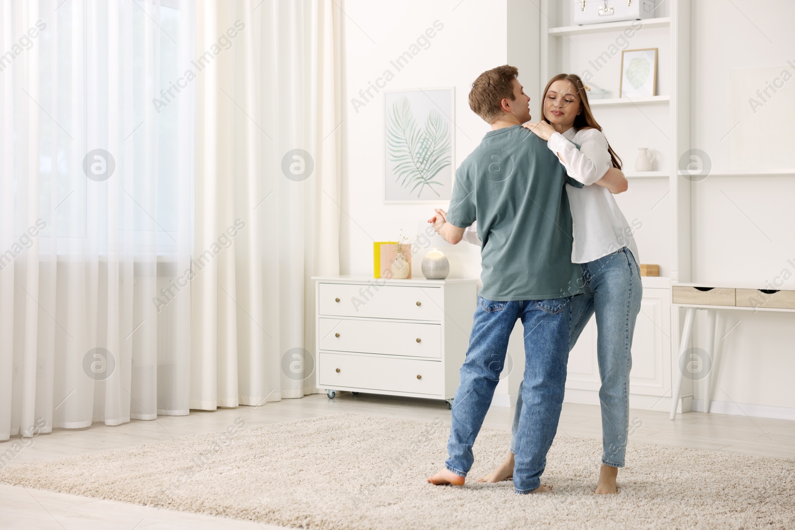 Photo of Young couple dancing together at home. Space for text