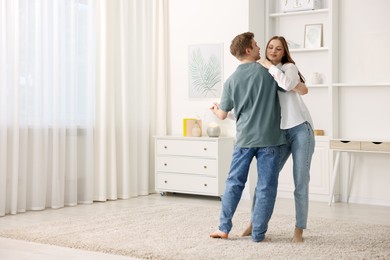 Photo of Young couple dancing together at home. Space for text