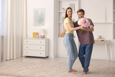 Photo of Happy young couple dancing together at home. Space for text