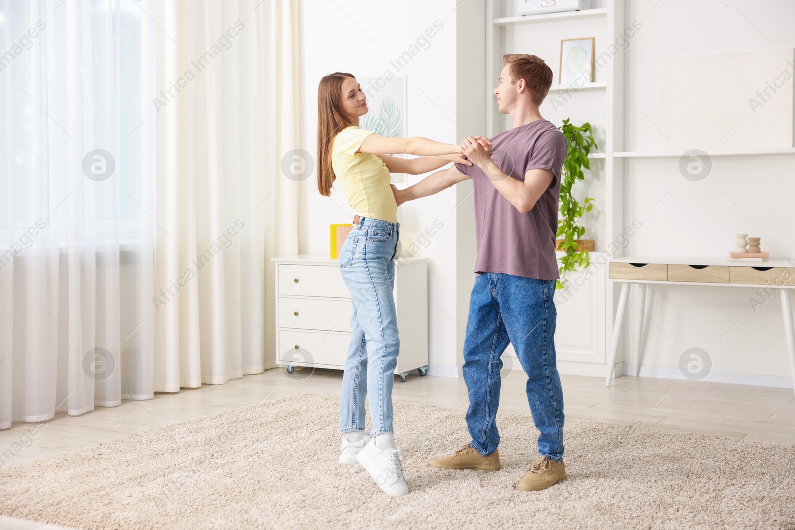 Photo of Carefree young couple dancing together at home