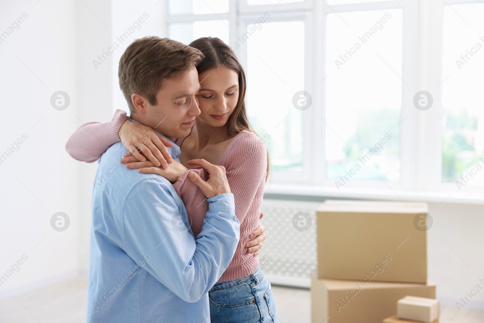Photo of Young couple dancing and cardboard boxes at home. Moving day