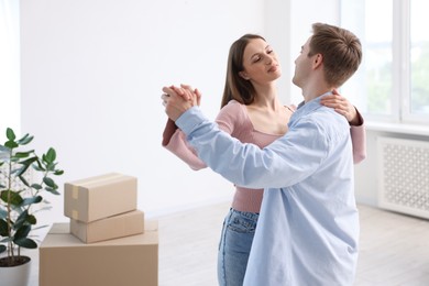Photo of Young couple dancing and cardboard boxes at home. Moving day