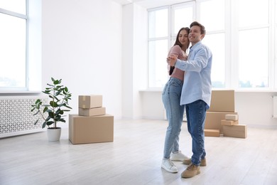 Photo of Happy young couple dancing and cardboard boxes at home, low angle view. Moving day