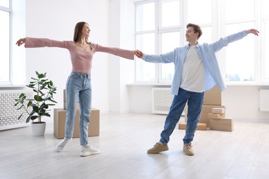 Photo of Happy young couple dancing and cardboard boxes at home, low angle view. Moving day