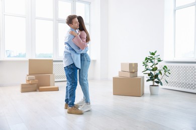 Photo of Happy young couple dancing and cardboard boxes at home. Moving day
