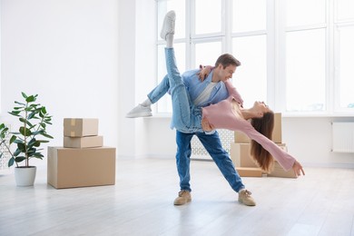 Photo of Happy young couple dancing and cardboard boxes at home. Moving day