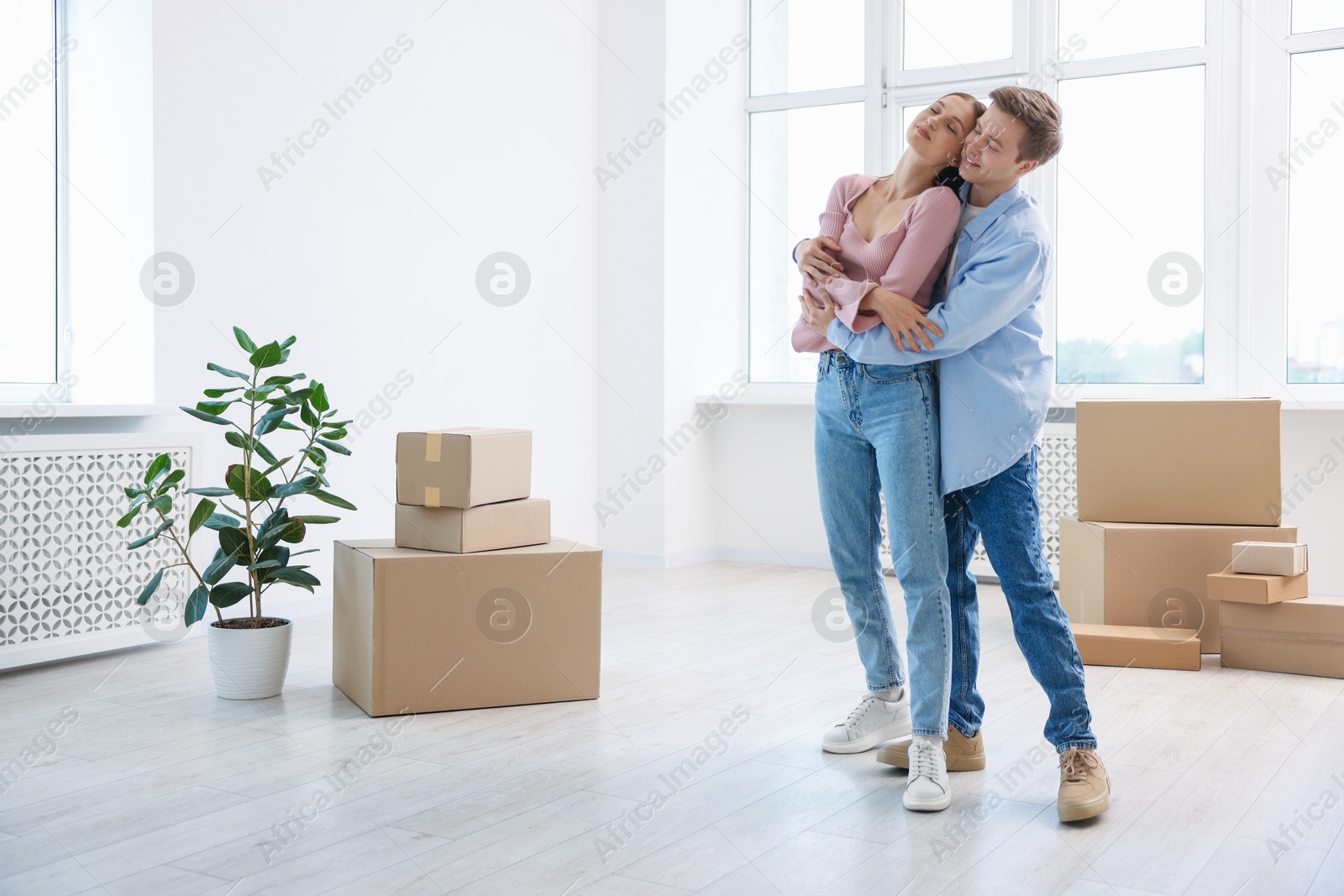 Photo of Happy young couple dancing and cardboard boxes at home. Moving day