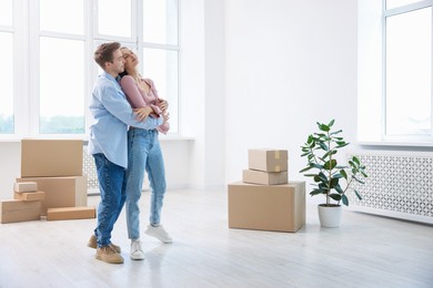 Photo of Young couple dancing and cardboard boxes at home. Moving day
