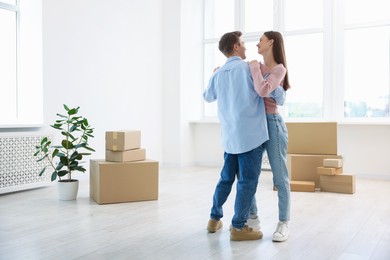 Photo of Young couple dancing and cardboard boxes at home. Moving day