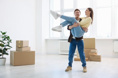 Photo of Happy young couple dancing and cardboard boxes at home. Moving day