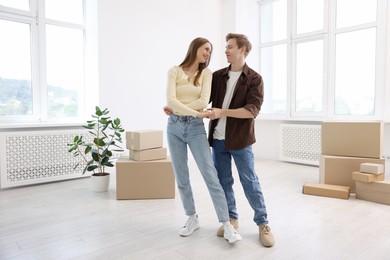 Photo of Happy young couple dancing and cardboard boxes at home. Moving day
