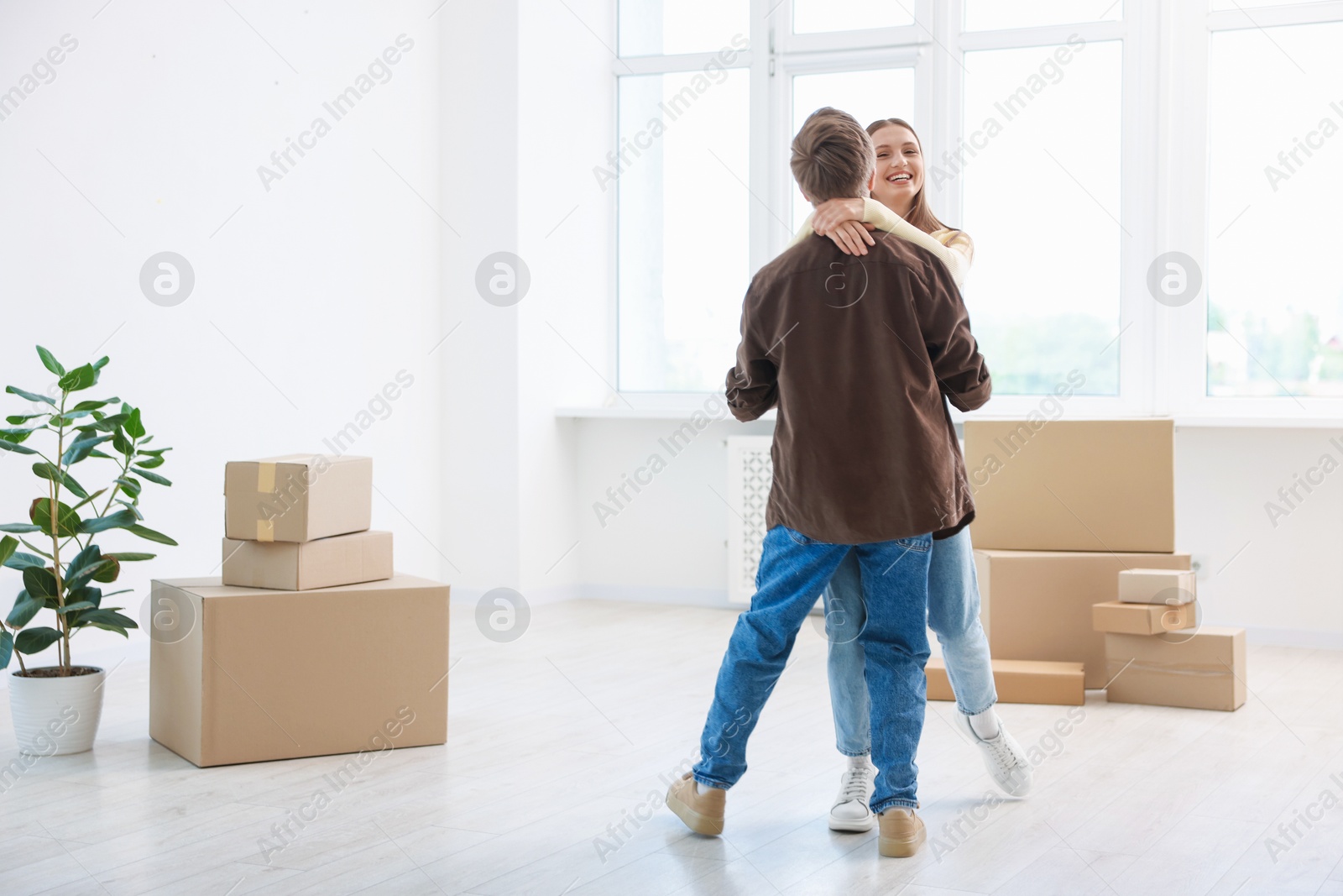 Photo of Happy young couple dancing among moving boxes at home