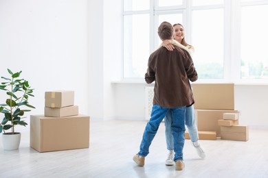 Photo of Happy young couple dancing among moving boxes at home
