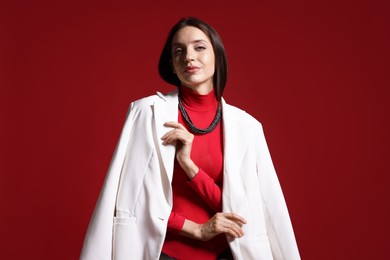 Photo of Portrait of beautiful woman in stylish outfit on red background