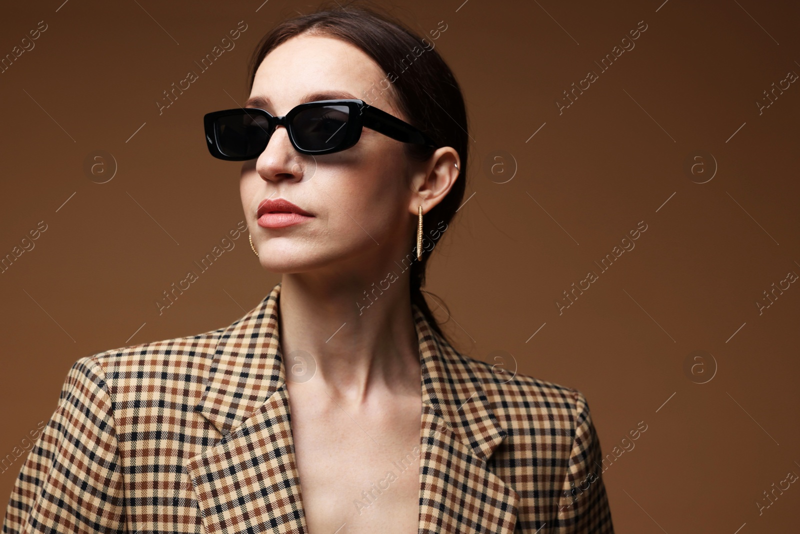 Photo of Portrait of beautiful woman in stylish outfit on brown background