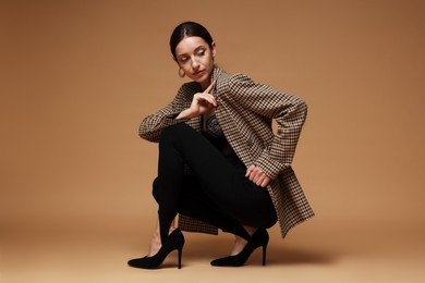 Photo of Full-length portrait of beautiful woman in stylish outfit on beige background