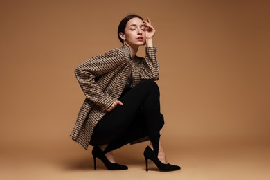 Photo of Full-length portrait of beautiful woman in stylish outfit on beige background