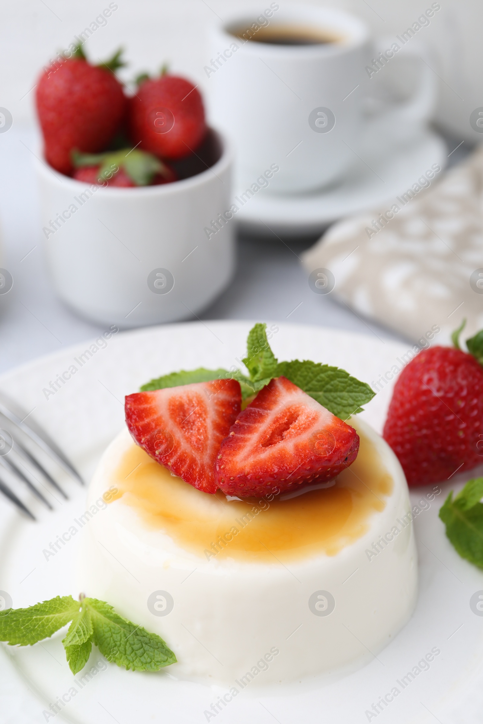 Tasty panna cotta with caramel, strawberries, mint and coffee on table, closeup Photo of Tasty panna cotta with caramel, strawberries, mint and coffee on table, closeup