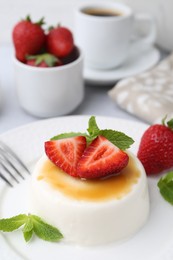 Photo of Tasty panna cotta with caramel, strawberries, mint and coffee on table, closeup