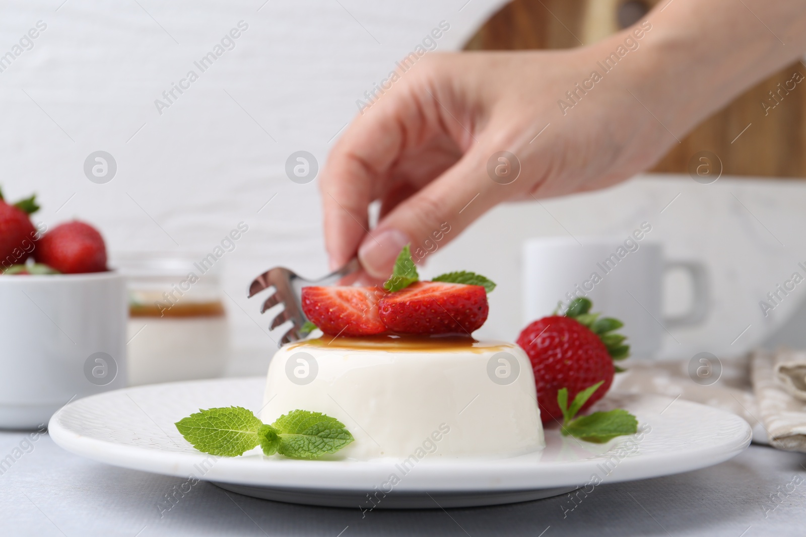 Woman eating tasty panna cotta at light table, closeup Photo of Woman eating tasty panna cotta at light table, closeup