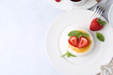 Photo of Tasty panna cotta with caramel, strawberries and mint on light table, flat lay. Space for text