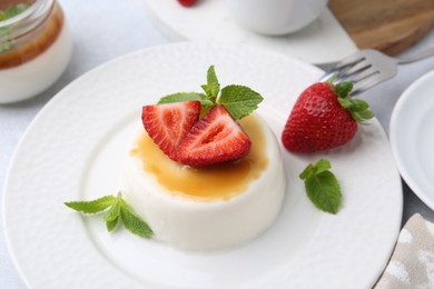 Photo of Tasty panna cotta with caramel, strawberries and mint on table, above view