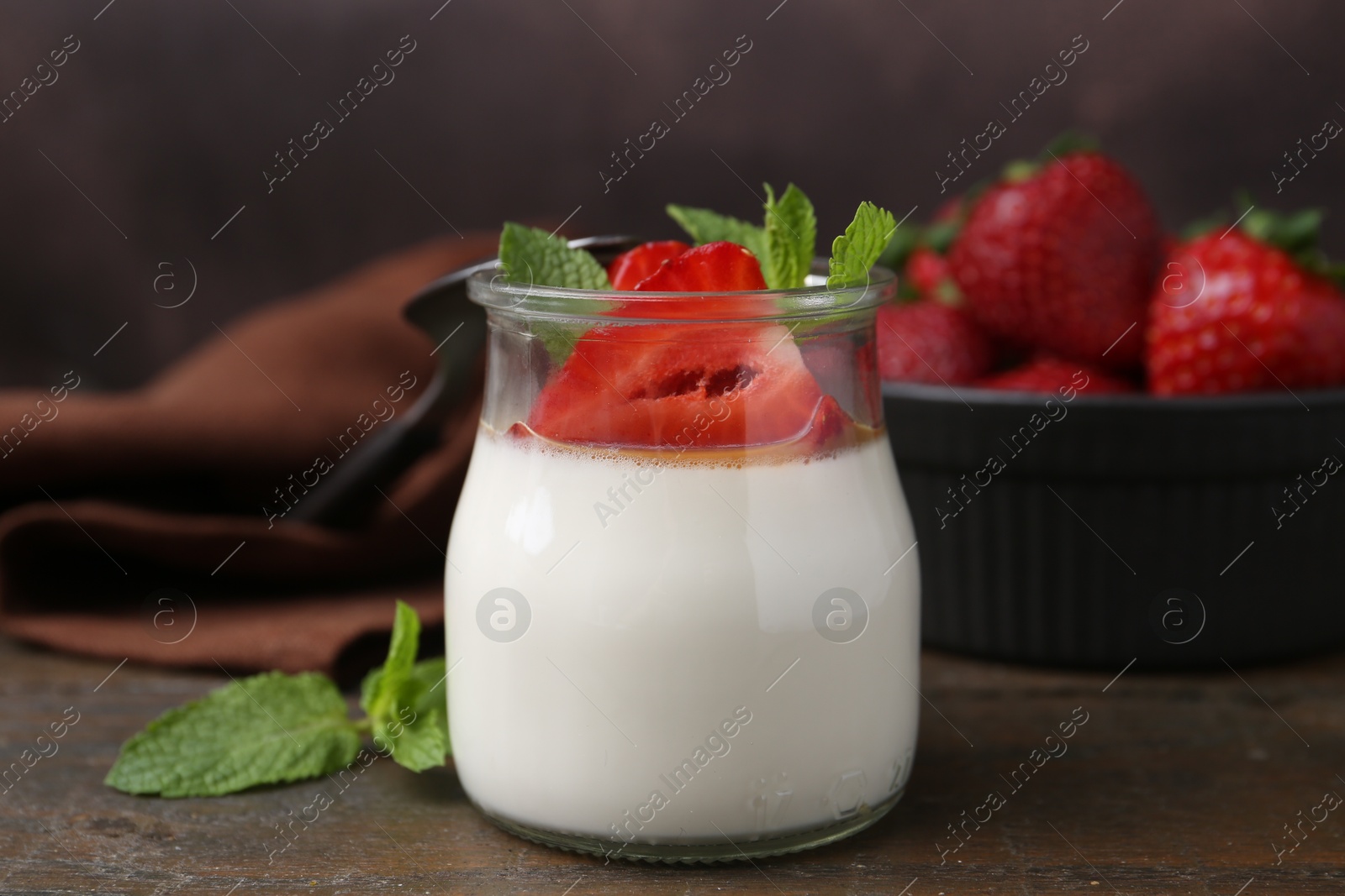 Tasty panna cotta with caramel, strawberries and mint on wooden table, closeup Photo of Tasty panna cotta with caramel, strawberries and mint on wooden table, closeup