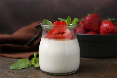Photo of Tasty panna cotta with caramel, strawberries and mint on wooden table, closeup