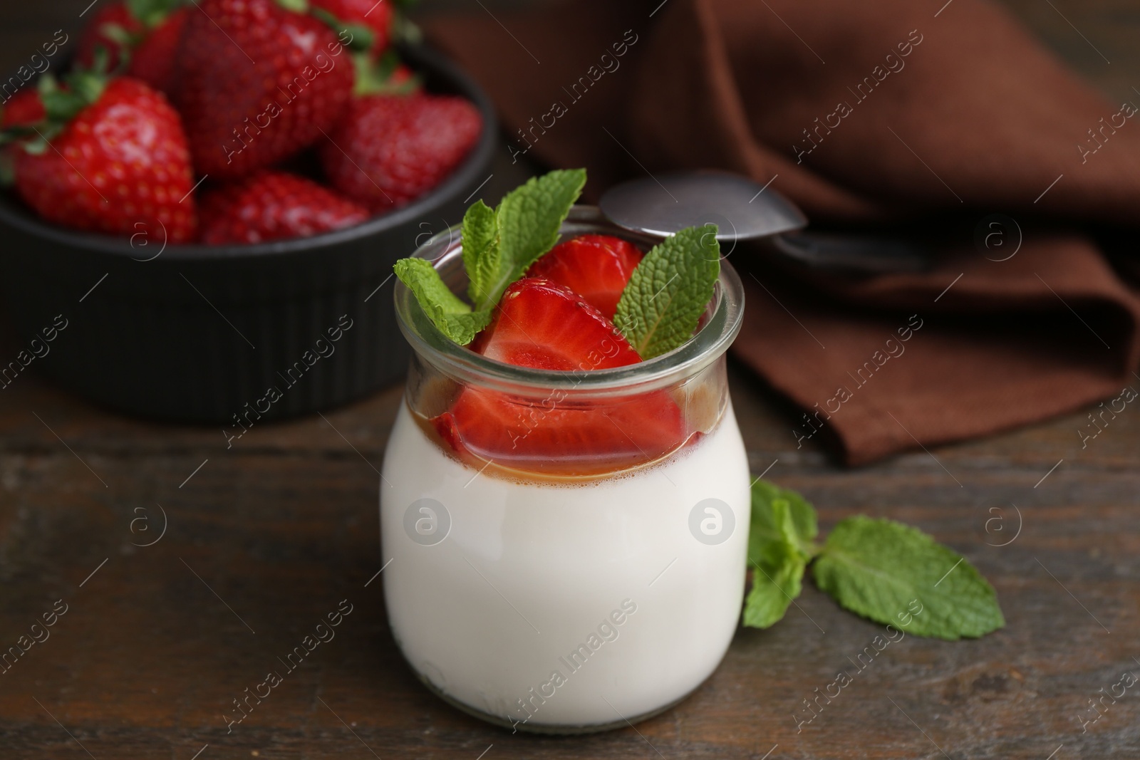 Tasty panna cotta with caramel, strawberries and mint on wooden table, closeup Photo of Tasty panna cotta with caramel, strawberries and mint on wooden table, closeup