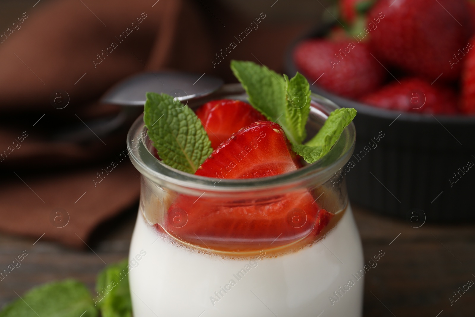 Tasty panna cotta with caramel, strawberries and mint on table, closeup Photo of Tasty panna cotta with caramel, strawberries and mint on table, closeup