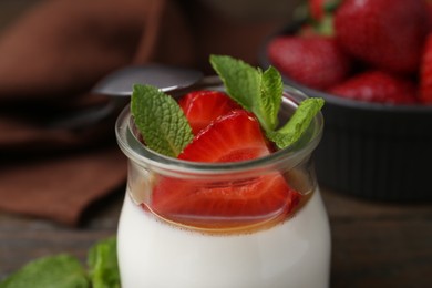 Photo of Tasty panna cotta with caramel, strawberries and mint on table, closeup
