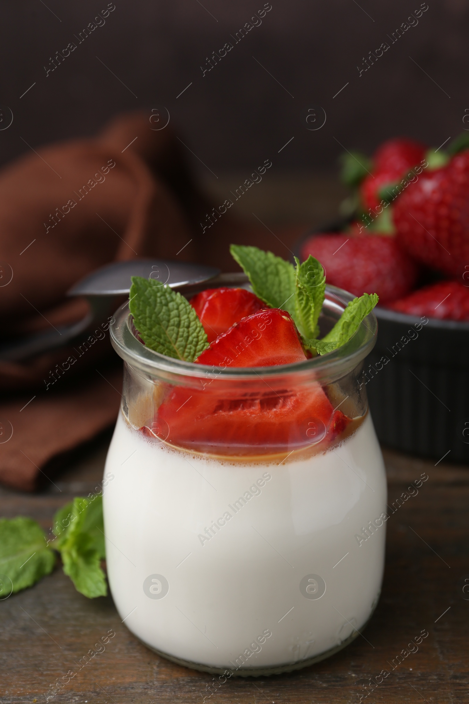 Tasty panna cotta with caramel, strawberries and mint on wooden table, closeup Photo of Tasty panna cotta with caramel, strawberries and mint on wooden table, closeup