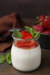 Photo of Tasty panna cotta with caramel, strawberries and mint on wooden table, closeup
