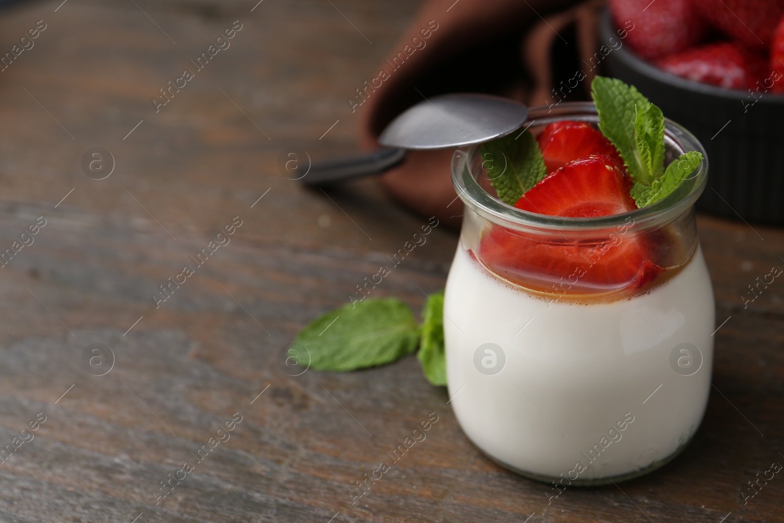Tasty panna cotta with caramel, strawberries and mint on wooden table, closeup. Space for text Photo of Tasty panna cotta with caramel, strawberries and mint on wooden table, closeup. Space for text