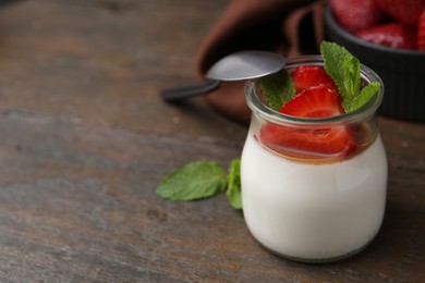 Photo of Tasty panna cotta with caramel, strawberries and mint on wooden table, closeup. Space for text