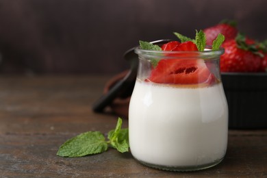 Photo of Tasty panna cotta with caramel, strawberries and mint on wooden table, closeup. Space for text