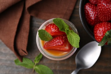 Photo of Tasty panna cotta with caramel, strawberries and mint on table, flat lay