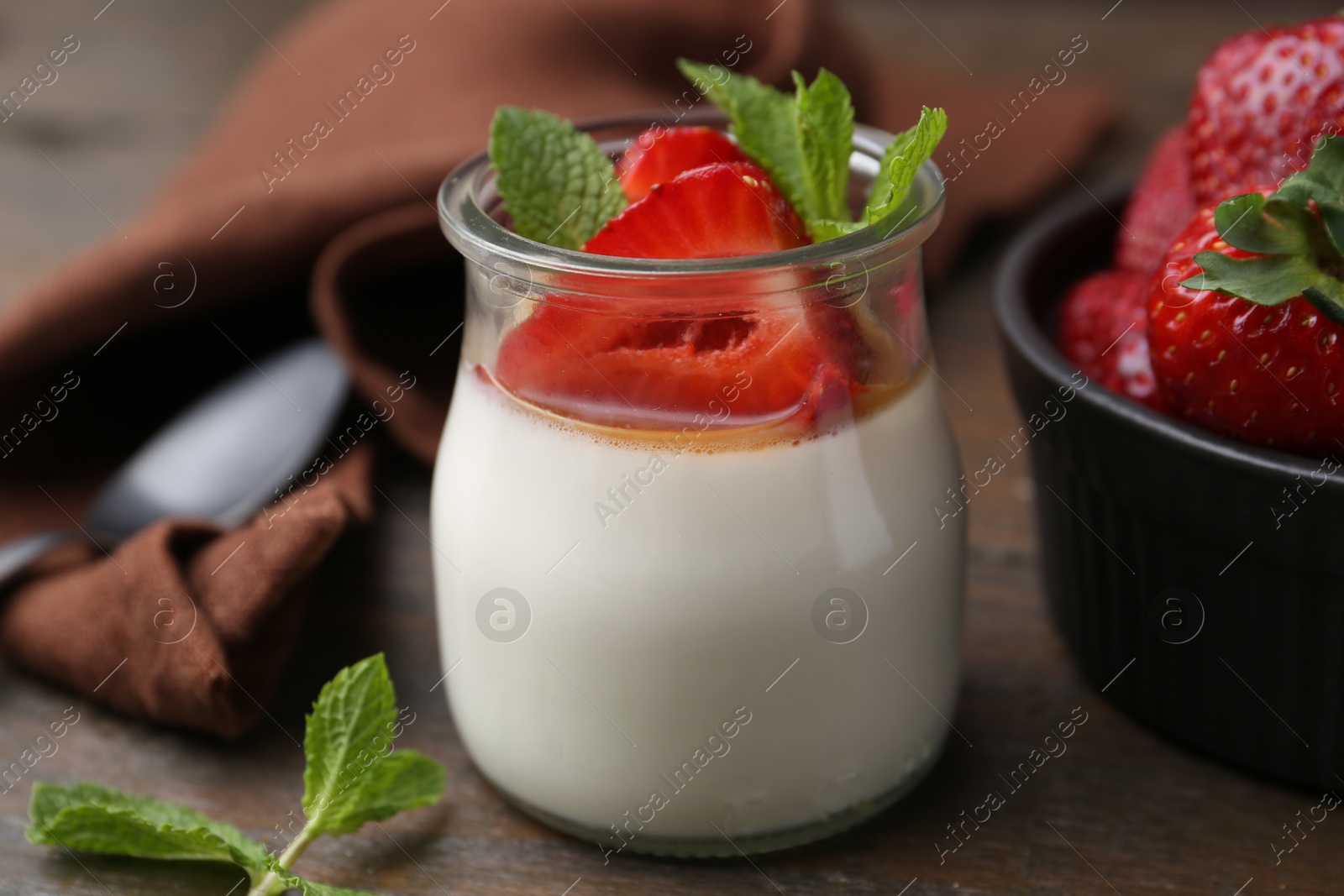 Tasty panna cotta with caramel, strawberries and mint on wooden table, closeup Photo of Tasty panna cotta with caramel, strawberries and mint on wooden table, closeup