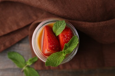 Photo of Tasty panna cotta with caramel, strawberries and mint on table, flat lay