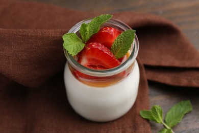 Photo of Tasty panna cotta with caramel, strawberries and mint on table, closeup