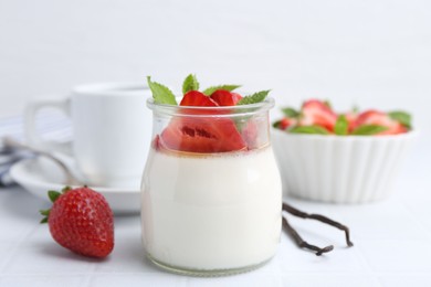 Photo of Tasty panna cotta with caramel, strawberries, mint and vanilla pods on white table, closeup