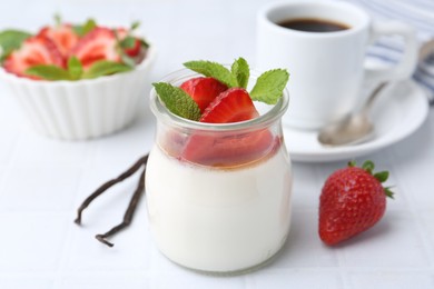 Photo of Tasty panna cotta with caramel, strawberries, mint, vanilla pods and coffee on white table, closeup