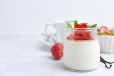 Photo of Tasty panna cotta with caramel, strawberries, mint and vanilla pods on white table, closeup. Space for text