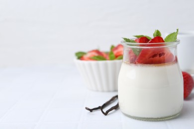 Photo of Tasty panna cotta with caramel, strawberries, mint and vanilla pods on white table, closeup. Space for text