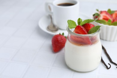 Photo of Tasty panna cotta with caramel, strawberries, mint, vanilla pods and coffee on white tiled table, closeup. Space for text