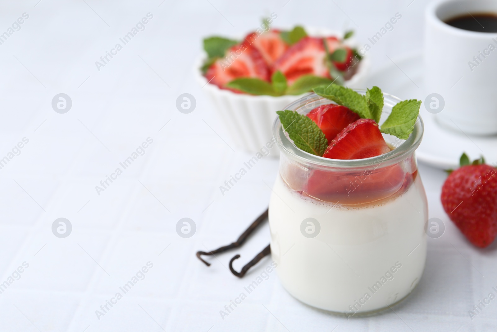 Tasty panna cotta with caramel, strawberries, mint, vanilla pods and coffee on white tiled table, closeup. Space for text Photo of Tasty panna cotta with caramel, strawberries, mint, vanilla pods and coffee on white tiled table, closeup. Space for text