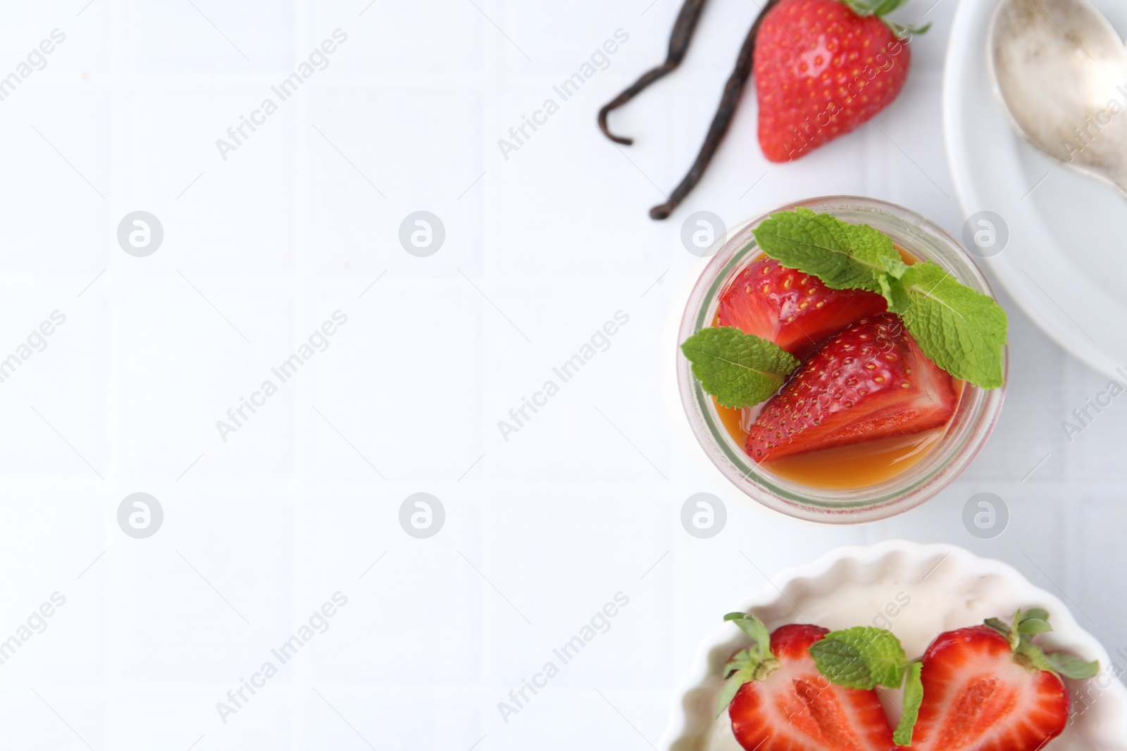 Tasty panna cotta with caramel, strawberries, mint and vanilla pods on white table, flat lay. Space for text Photo of Tasty panna cotta with caramel, strawberries, mint and vanilla pods on white table, flat lay. Space for text